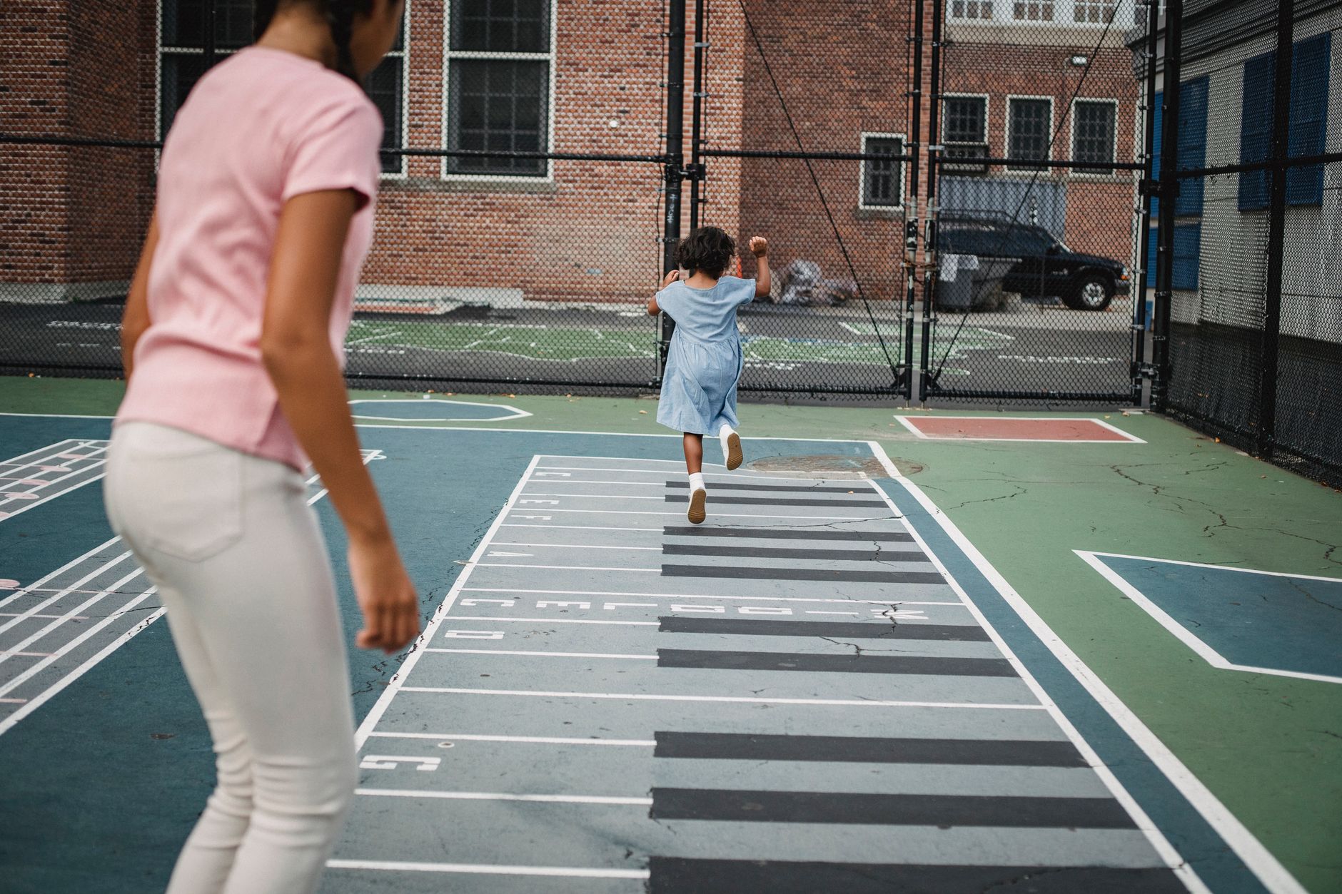 Two children enjoying a hopscotch game at an outdoor playground.