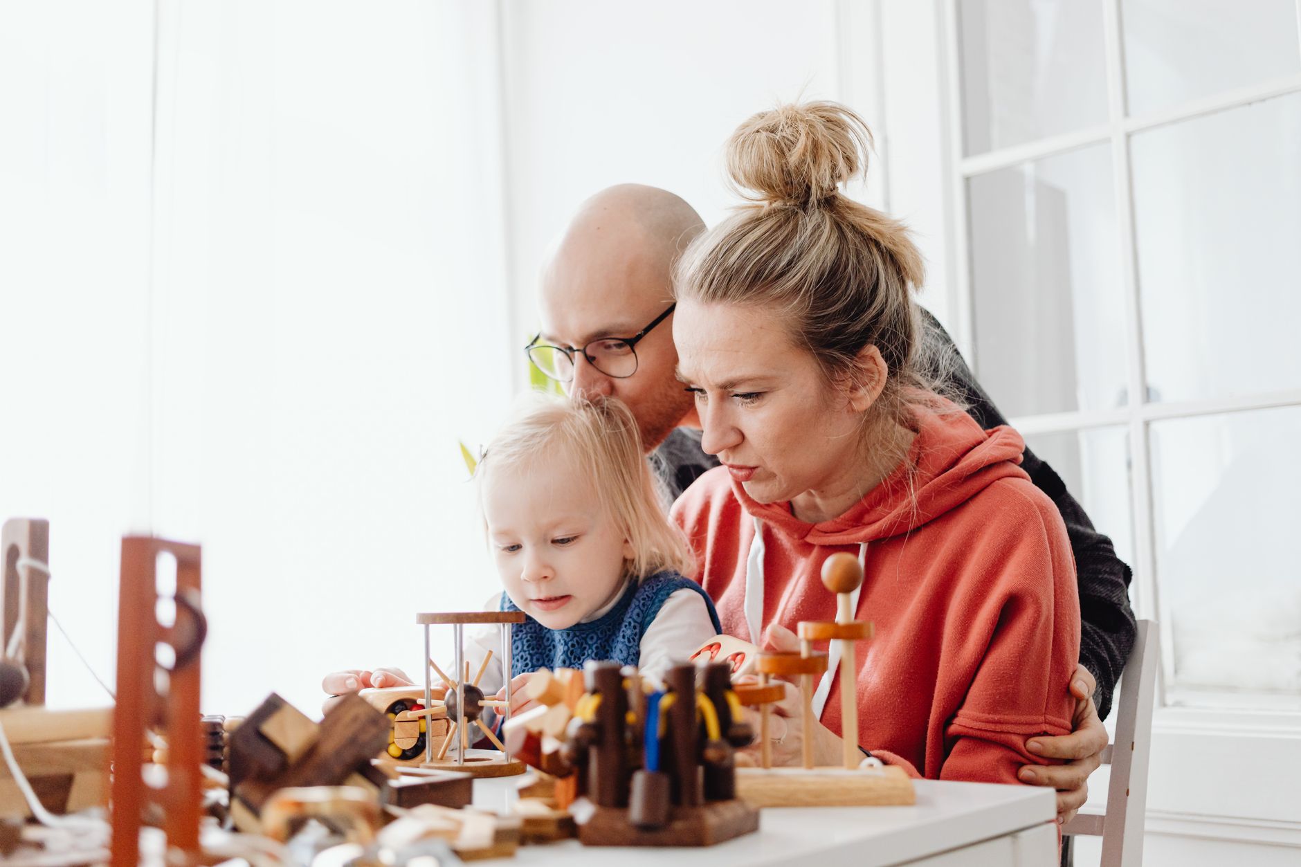 A family enjoys playing with wooden toys together indoors, promoting bonding and creativity.