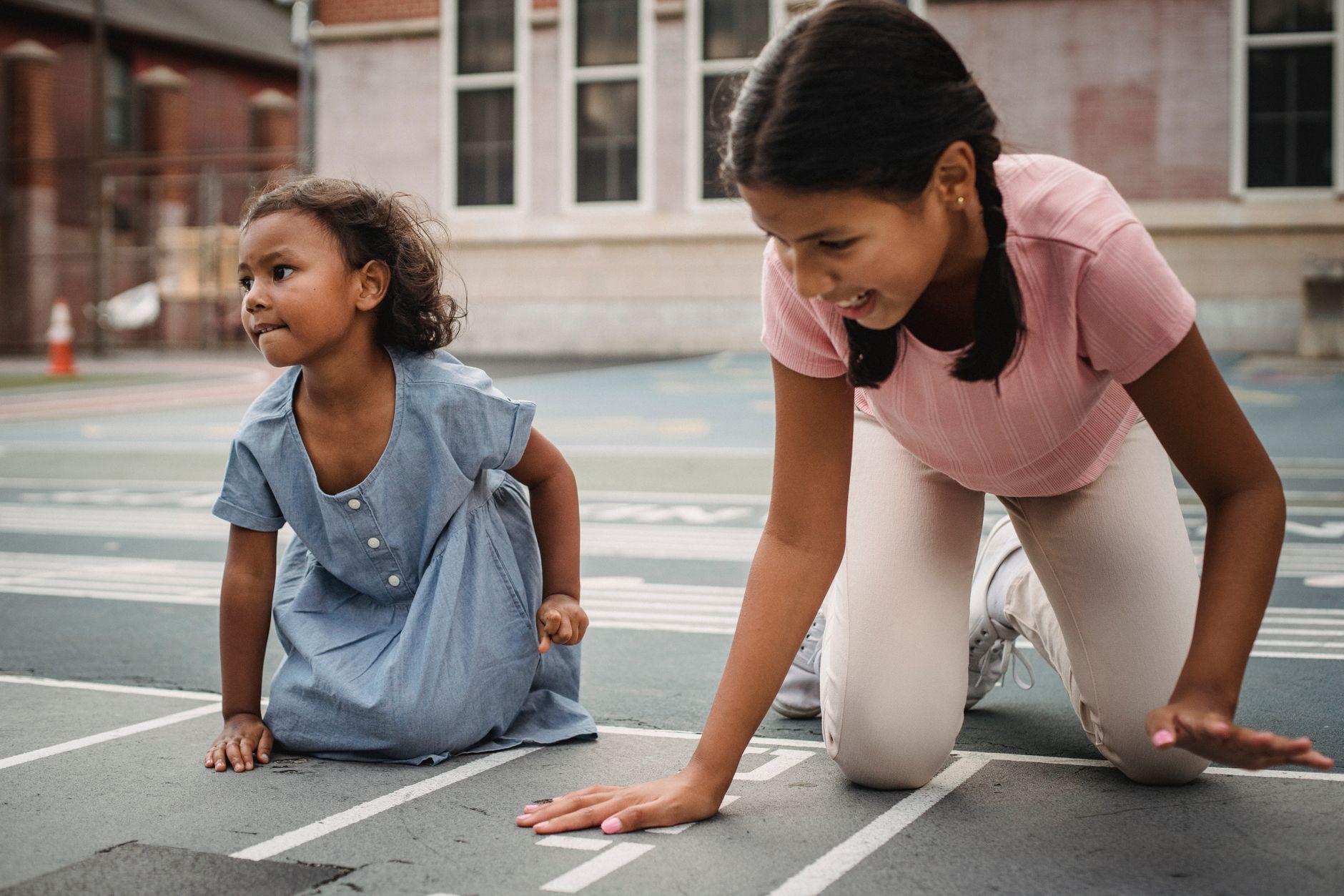 Two girls enjoy a playful moment on an outdoor school playground track.