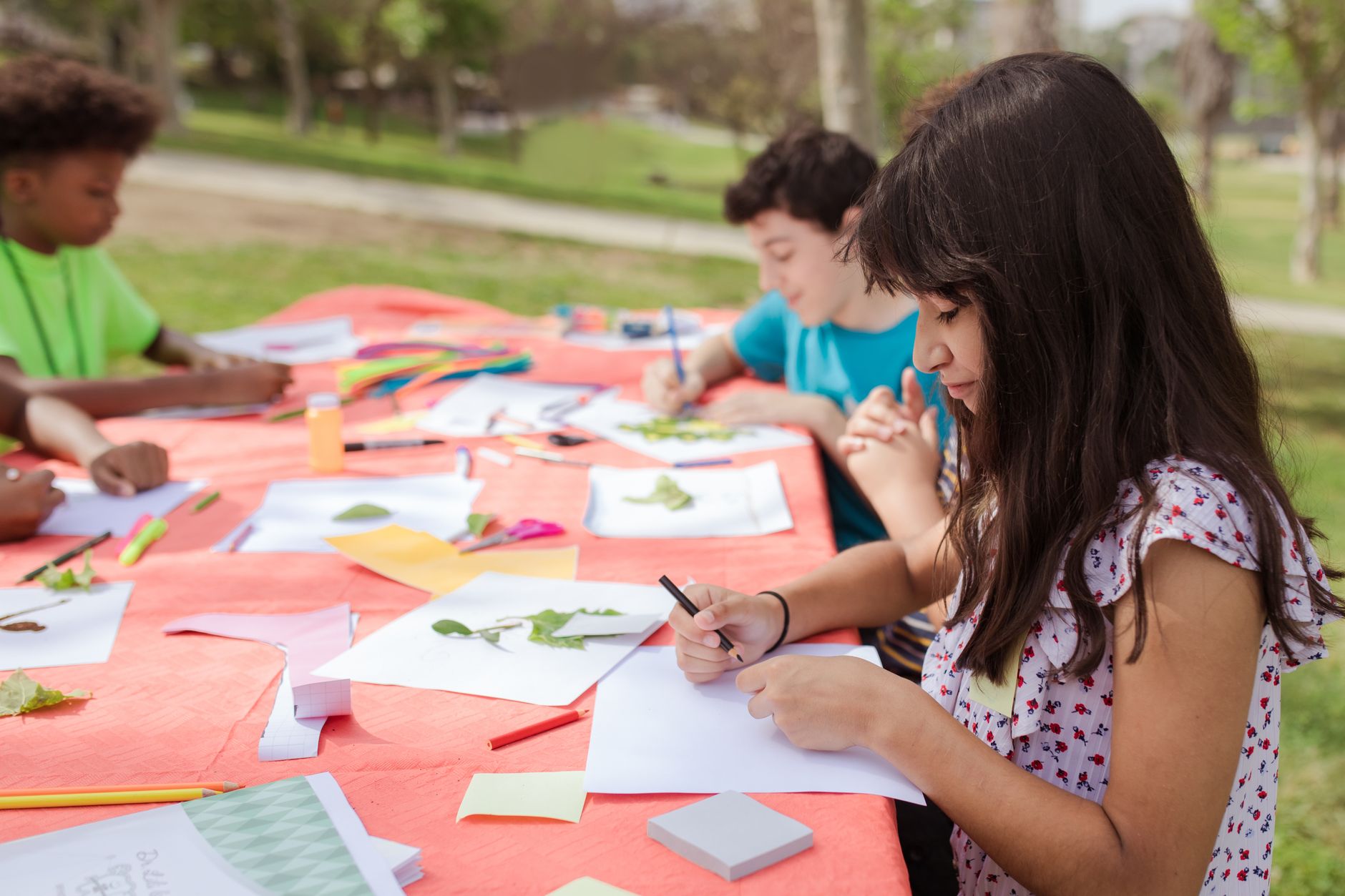 Children participating in outdoor art activities, creating crafts and drawings on a sunny day.
