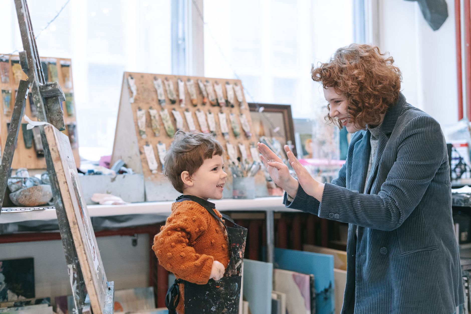 A joyful mother and son painting together in an art studio. Creative learning environment.