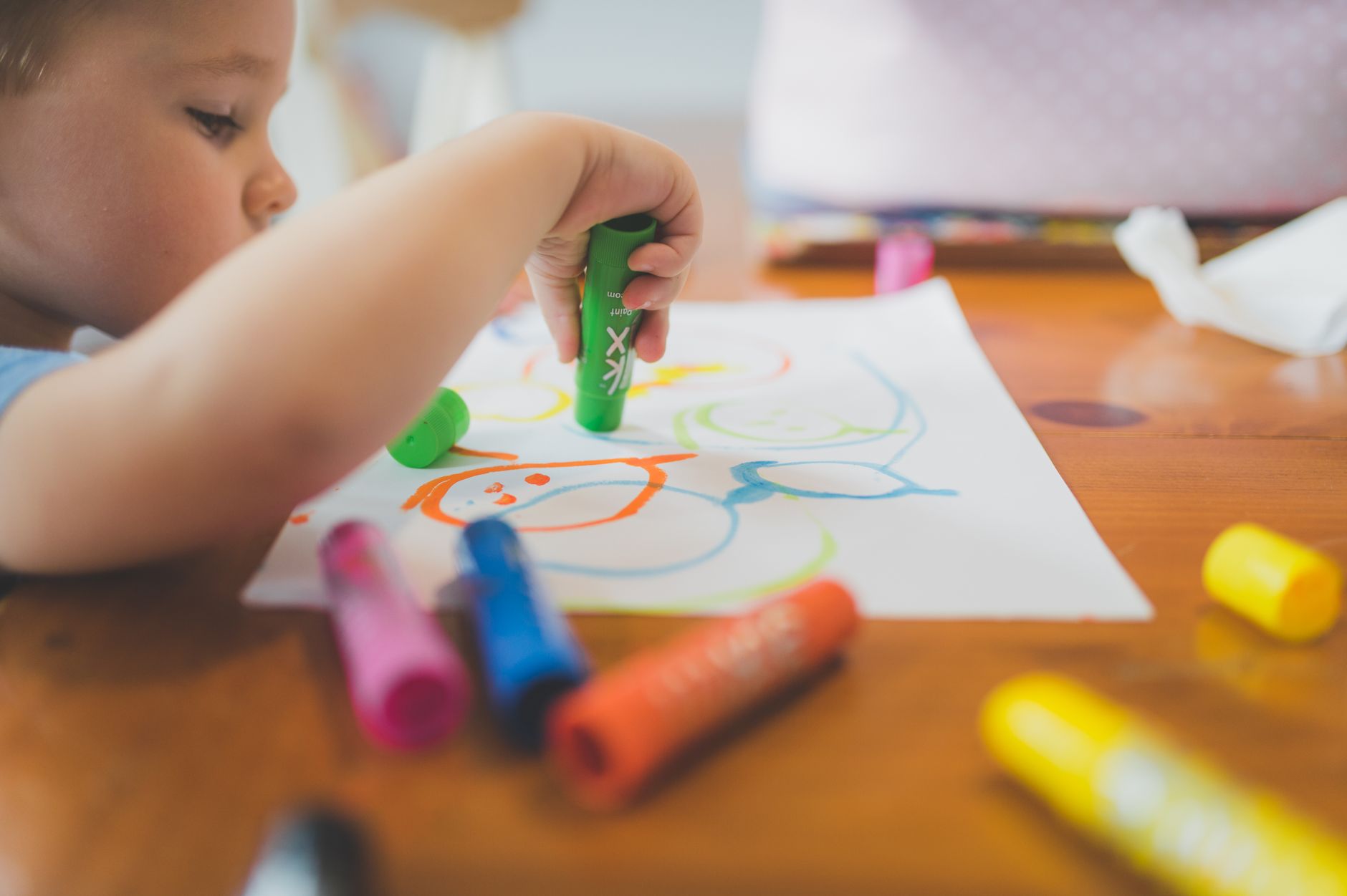 Close-up of a child drawing with vibrant markers, showcasing creativity and fun in an indoor setting.