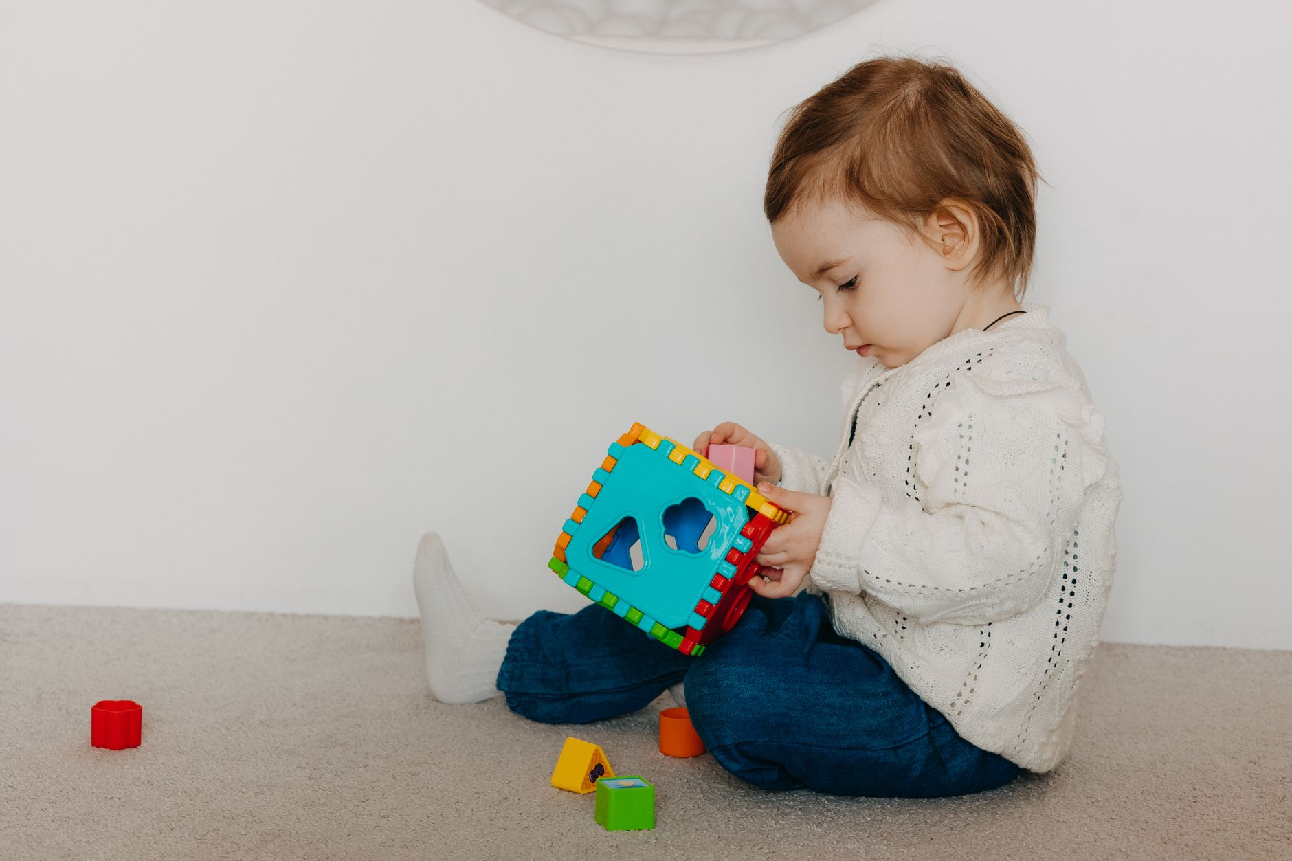 Cute toddler playing with colorful toy blocks indoors, showcasing innocence and joy.
