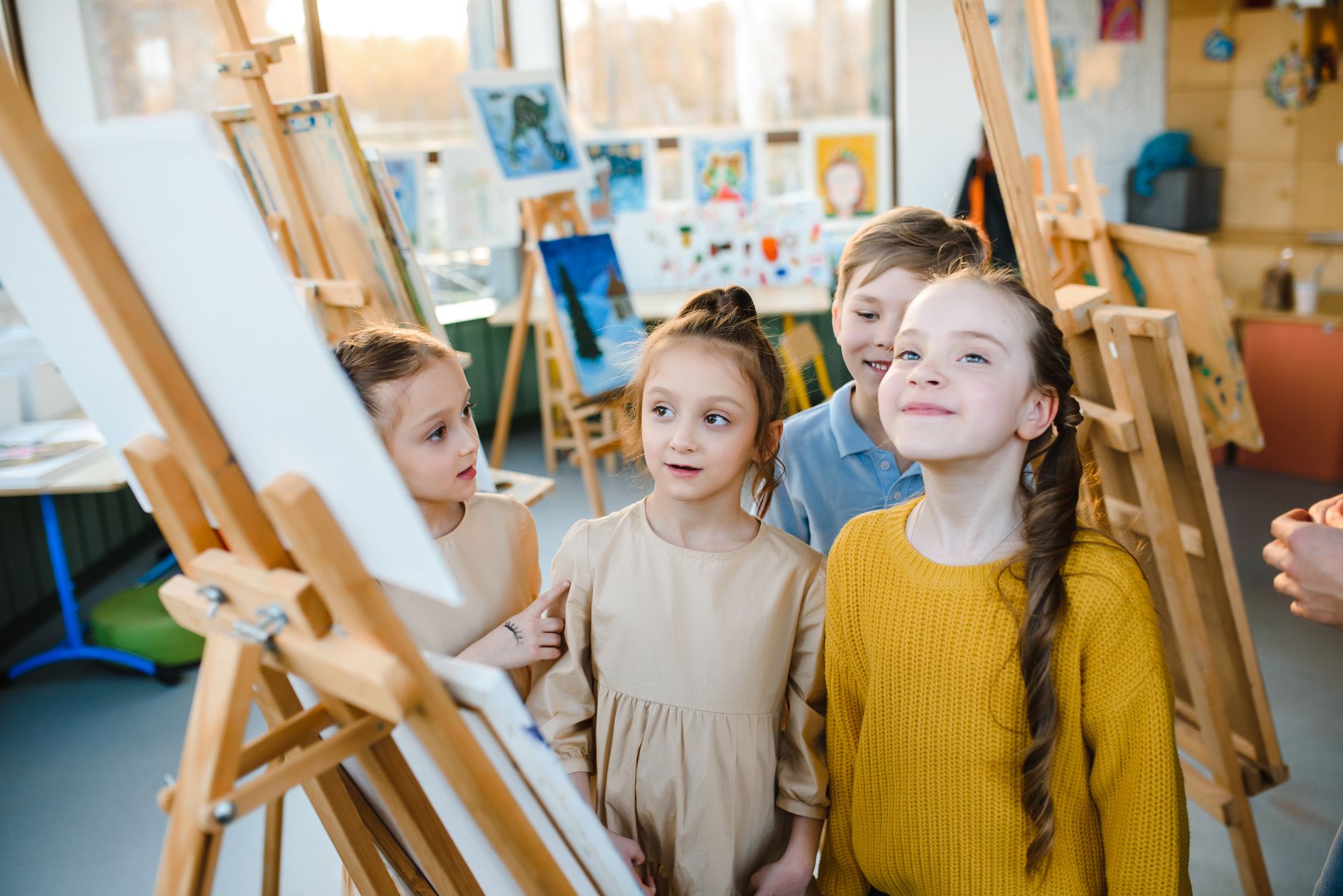 A group of children painting on easels in a bright, lively art class.