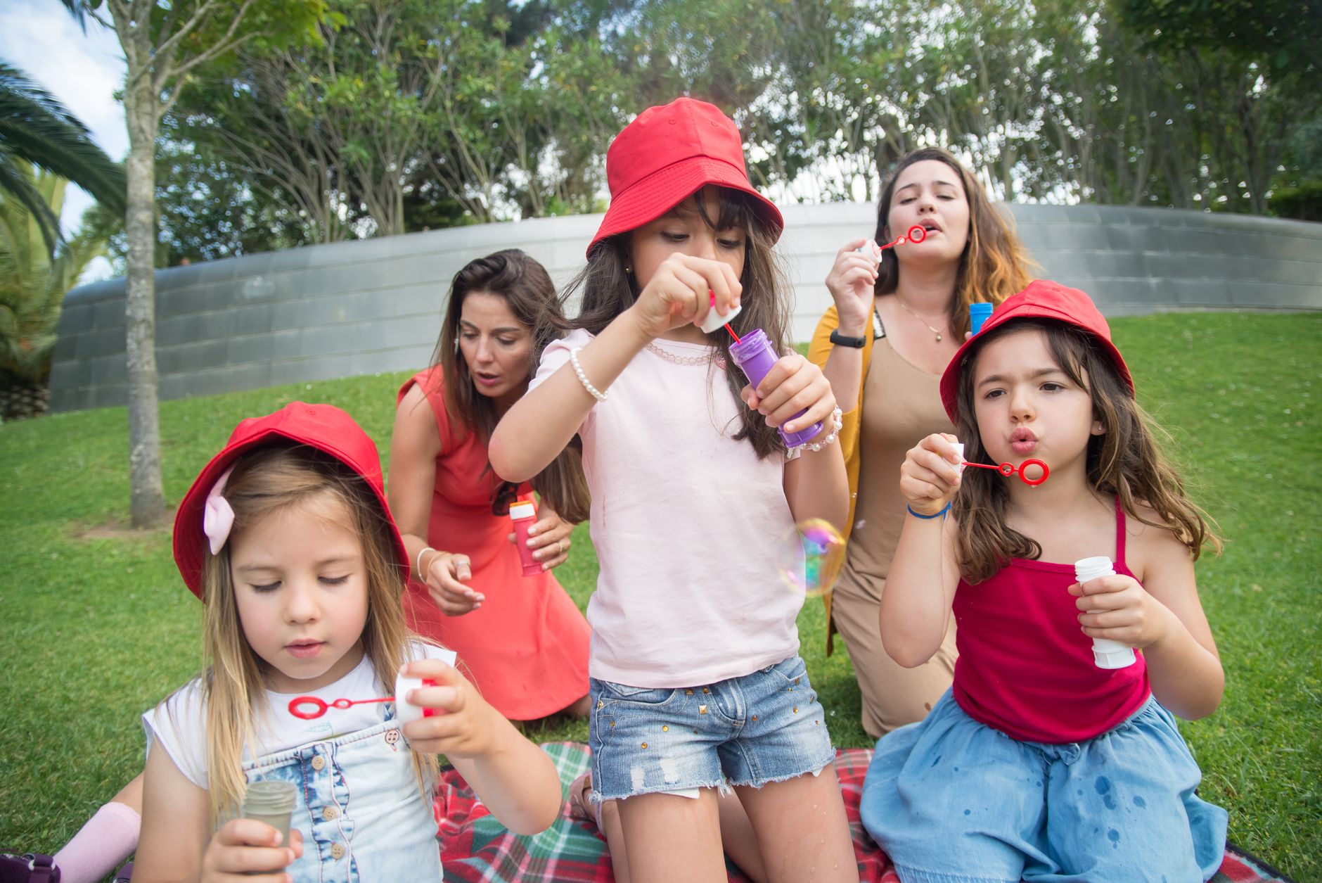 Happy children and adults enjoying bubble-blowing in a sunny park, creating joyful summer memories.