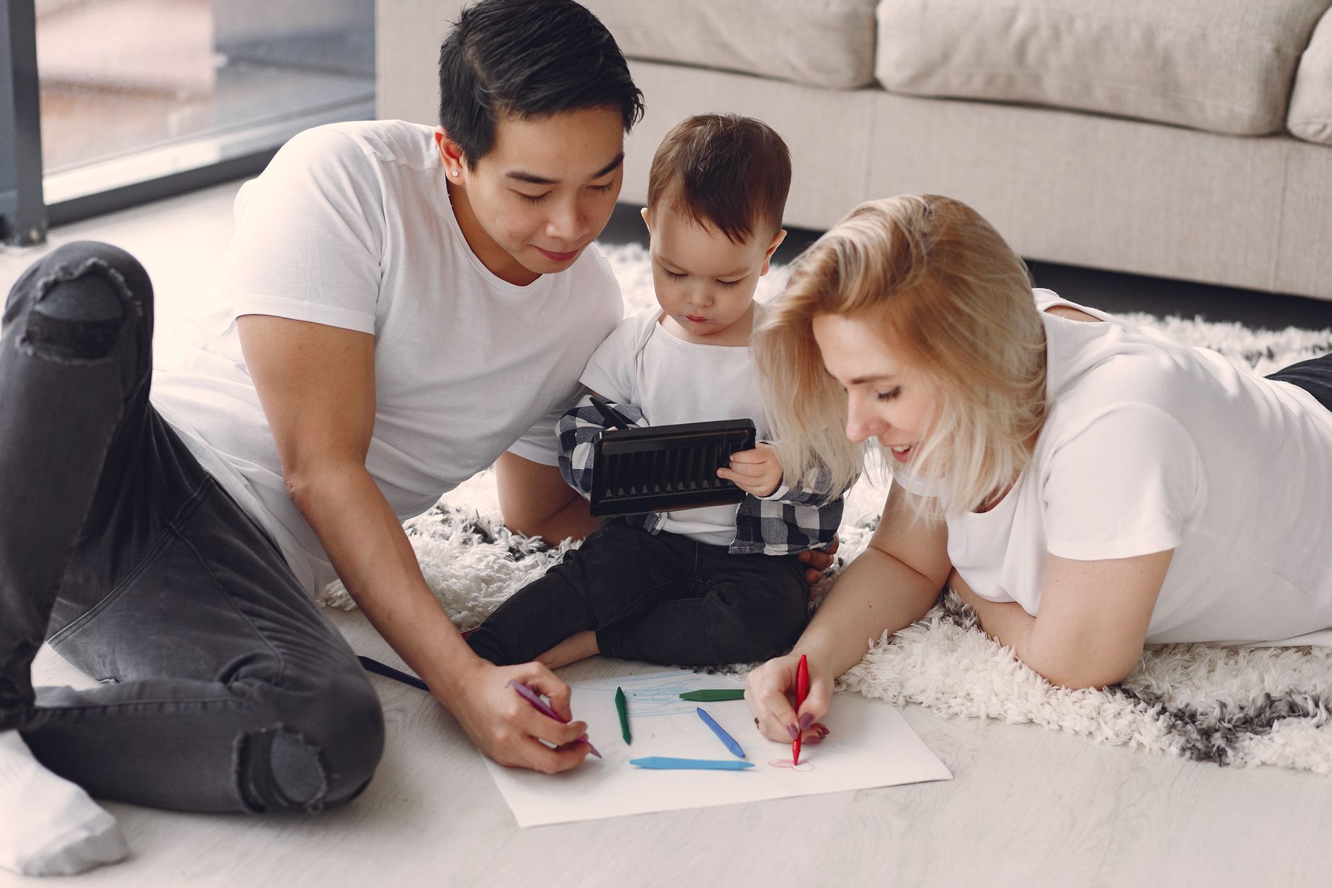 A loving family of three drawing together on the floor of their cozy living room.