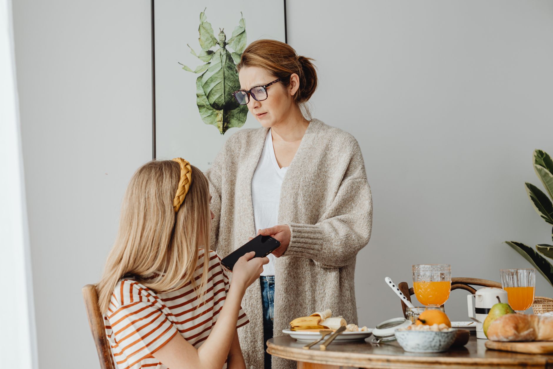 A mother correcting her teenage daughter's behavior during breakfast, conveying parenting dynamics.