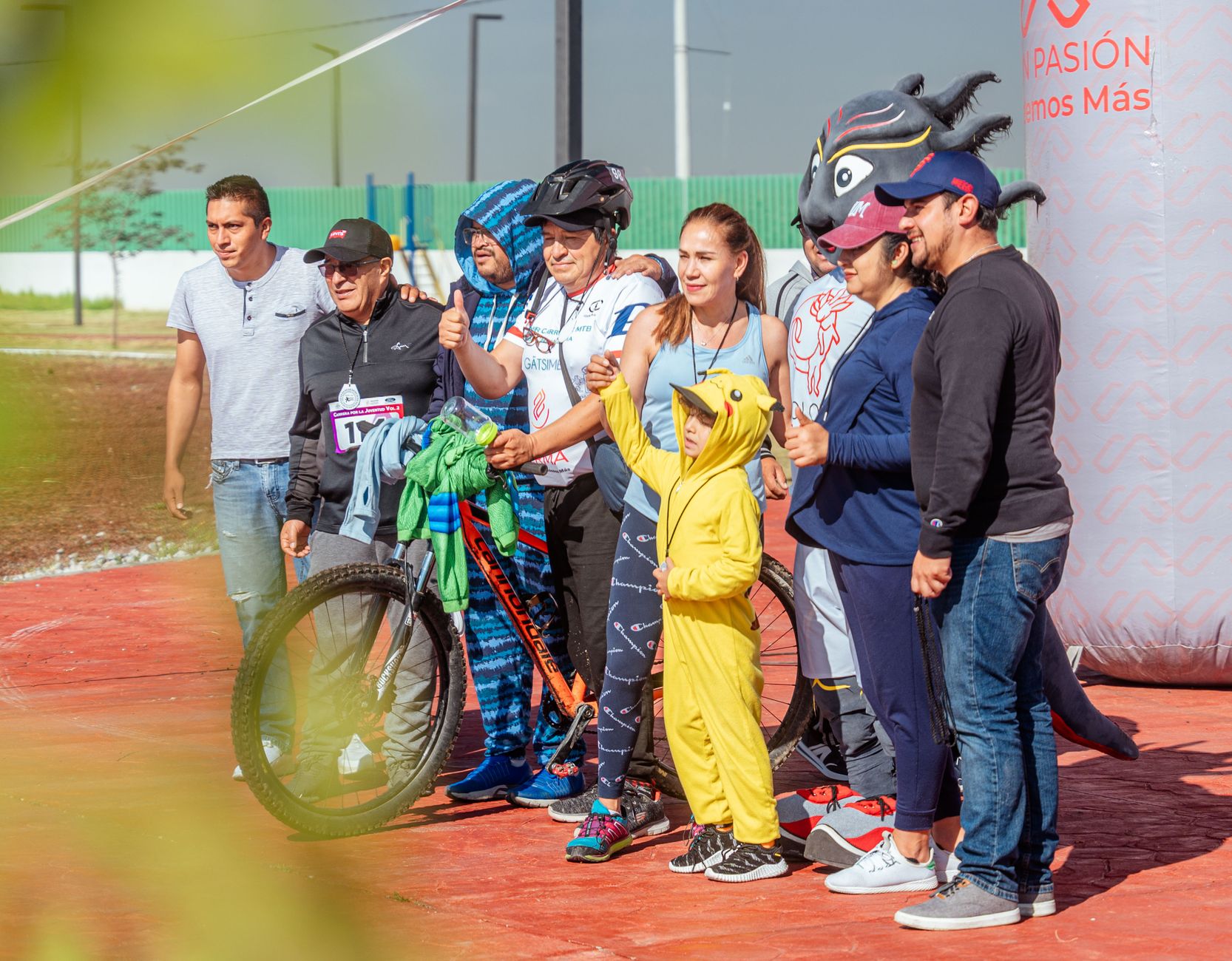 A diverse group poses with a bicycle at an outdoor cycling event, embracing fun and community.