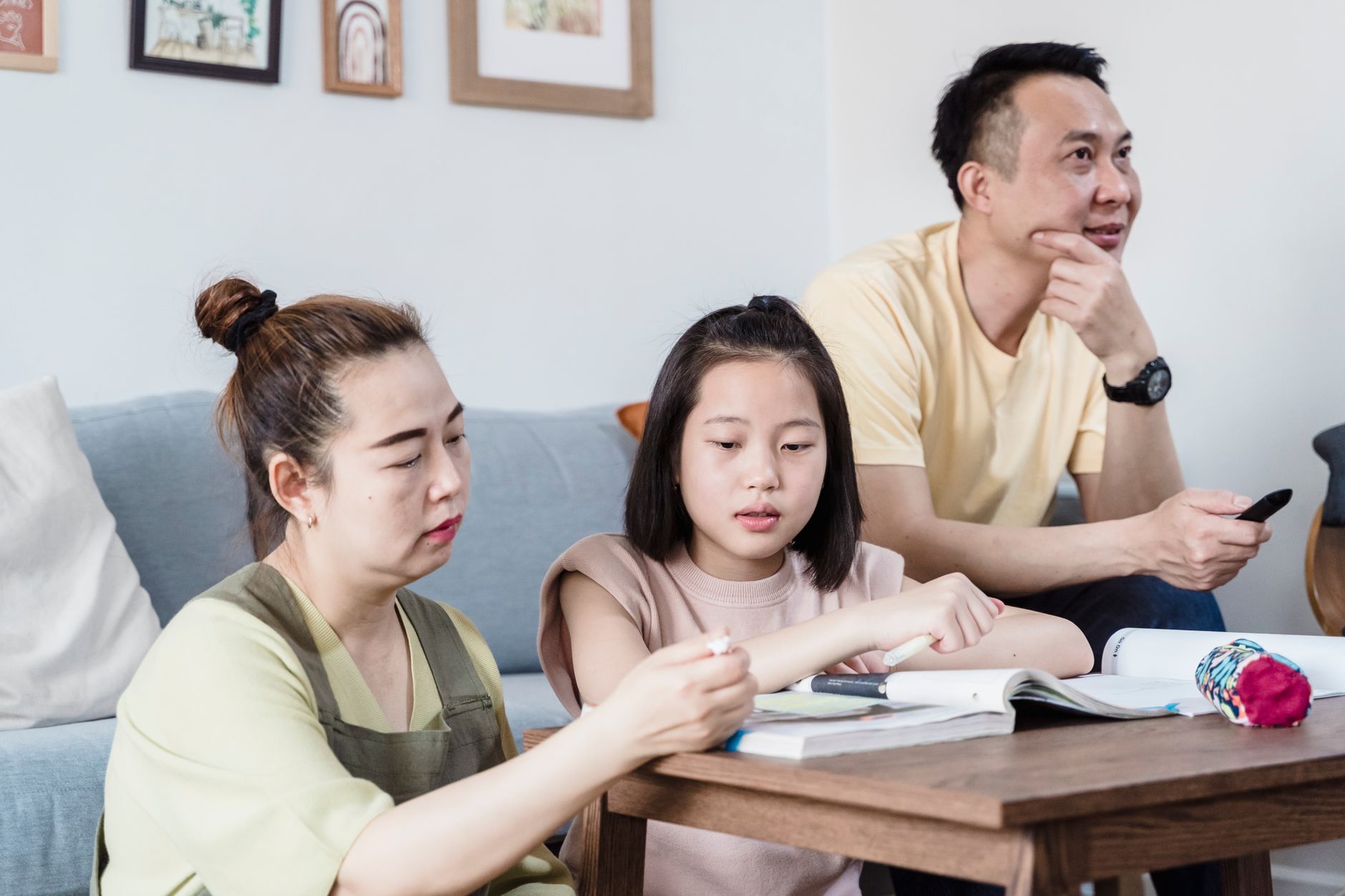 A family helping their daughter with homework in the living room, promoting togetherness.