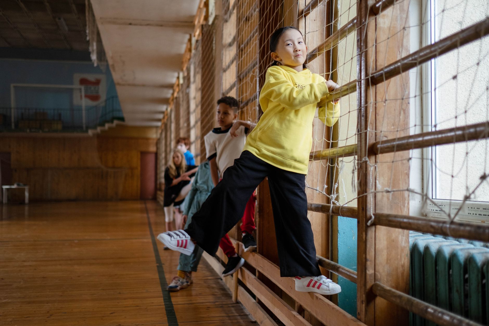 Young children play and climb in a wooden indoor gym, enjoying physical activity together.