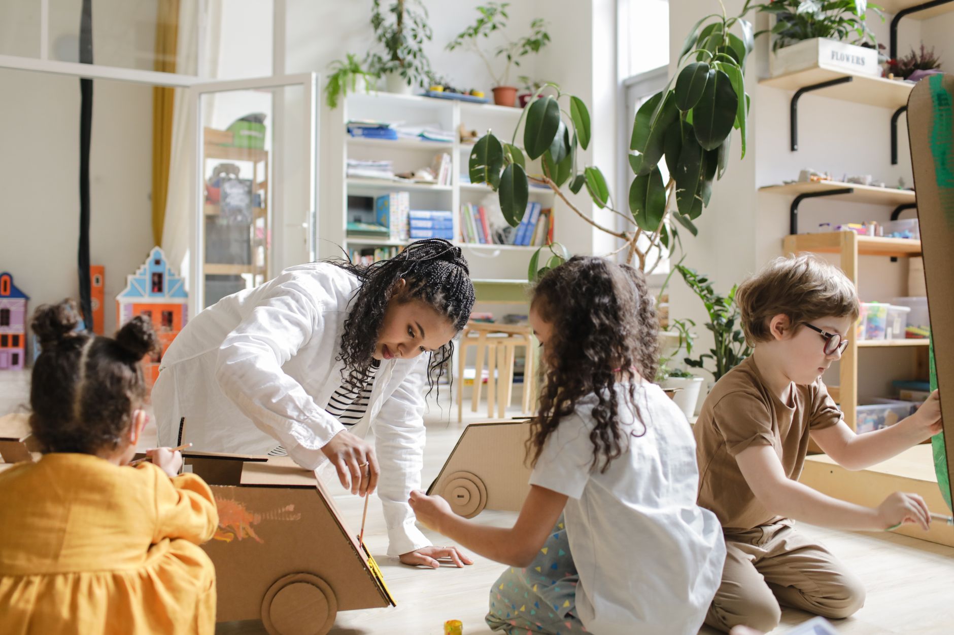 Children engaging in a creative art project with a teacher in a classroom.
