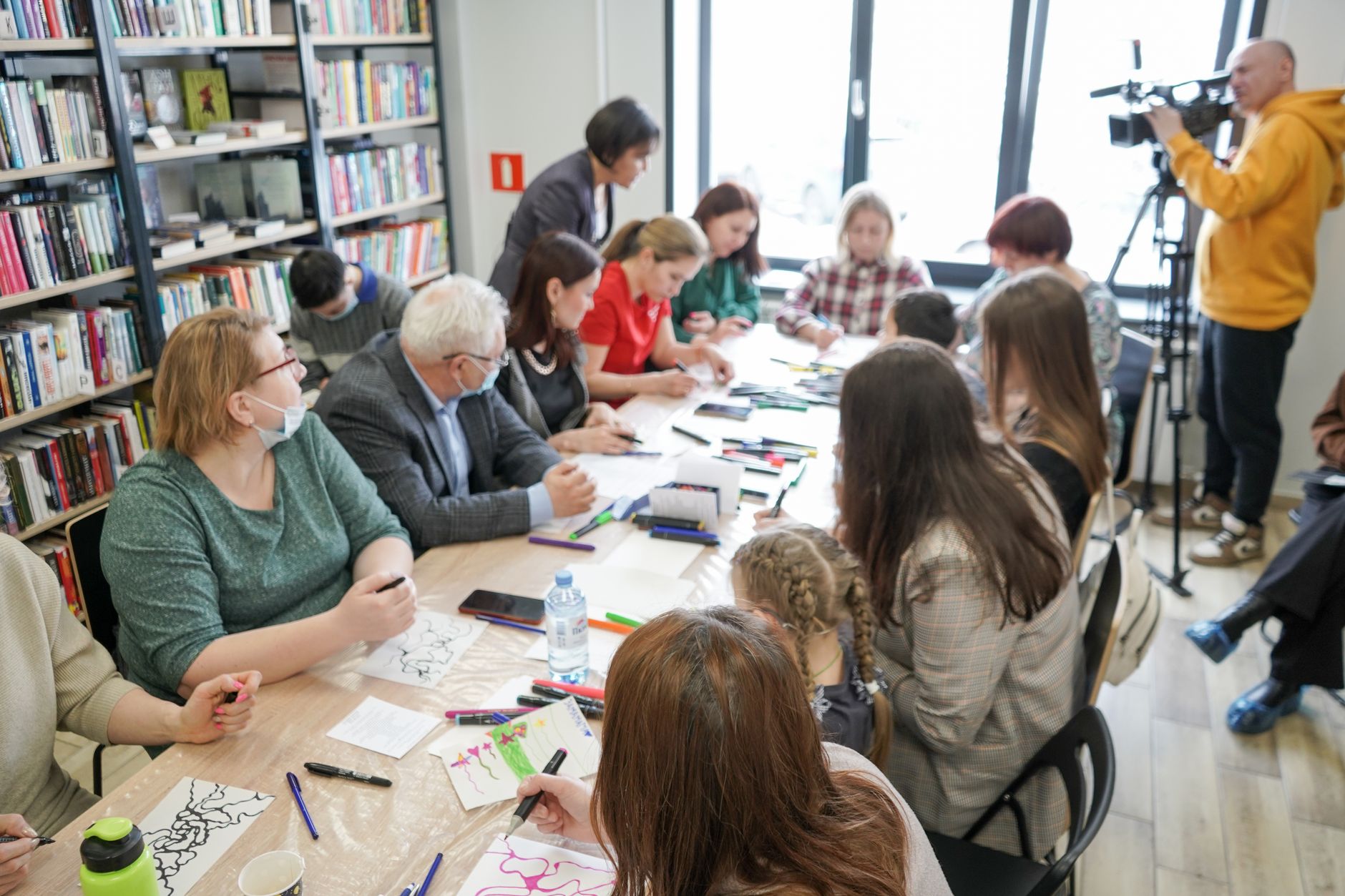 Group engaging in a creative workshop with art materials in a library setting.
