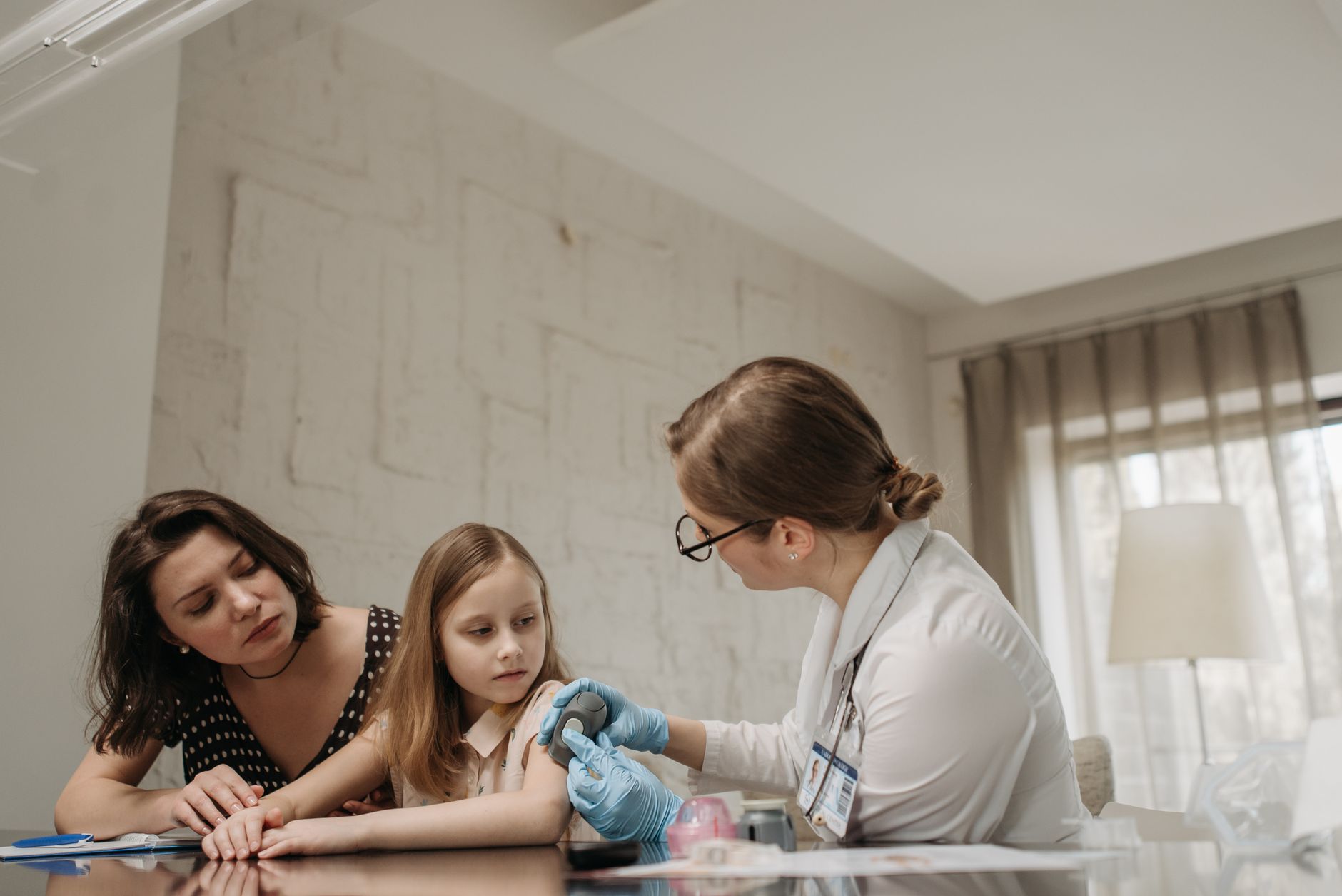 Mother and daughter consult with doctor about child vaccination in a medical office.