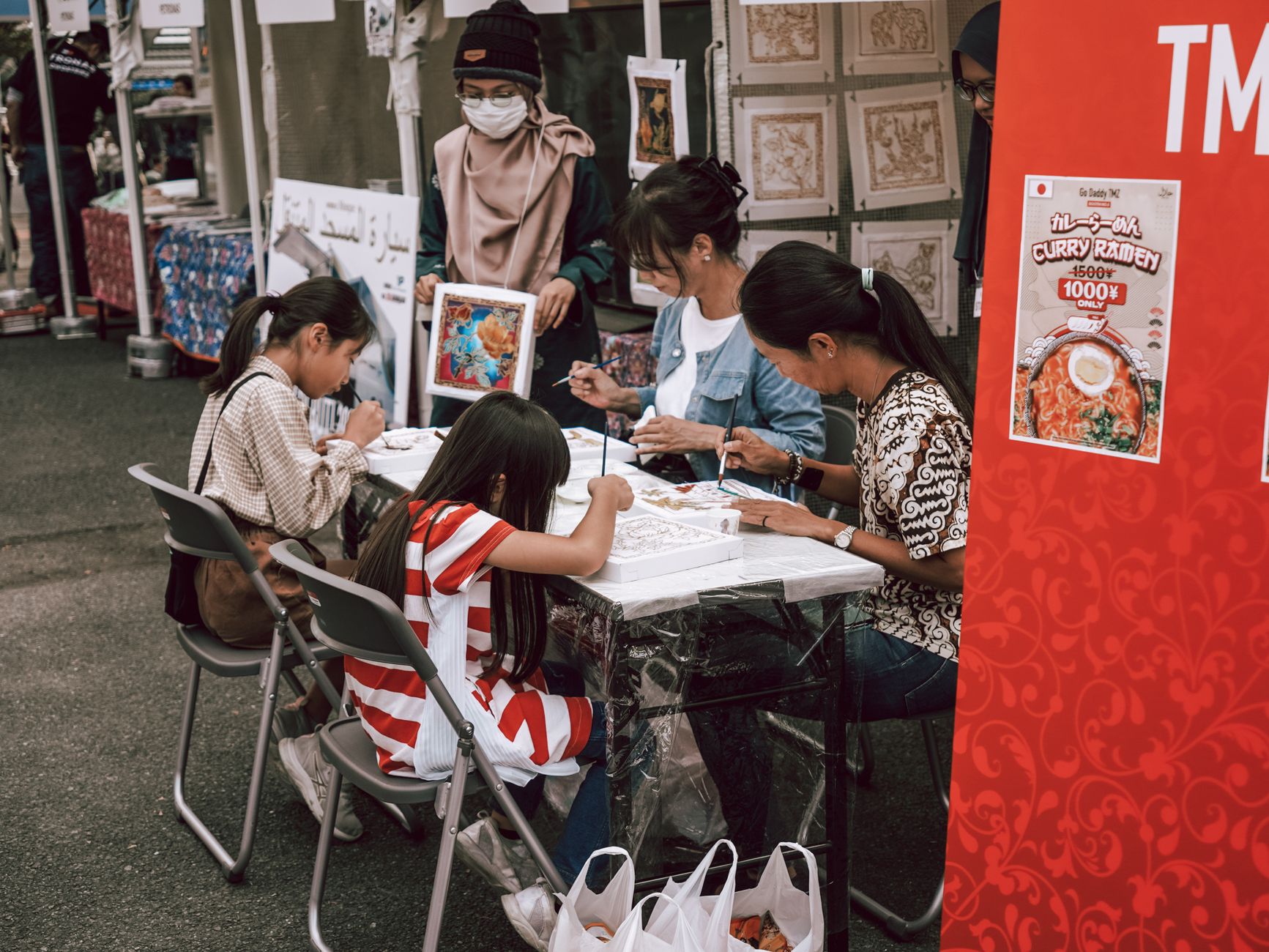 Family creating artwork together at an outdoor market. Engaging community event with children painting.