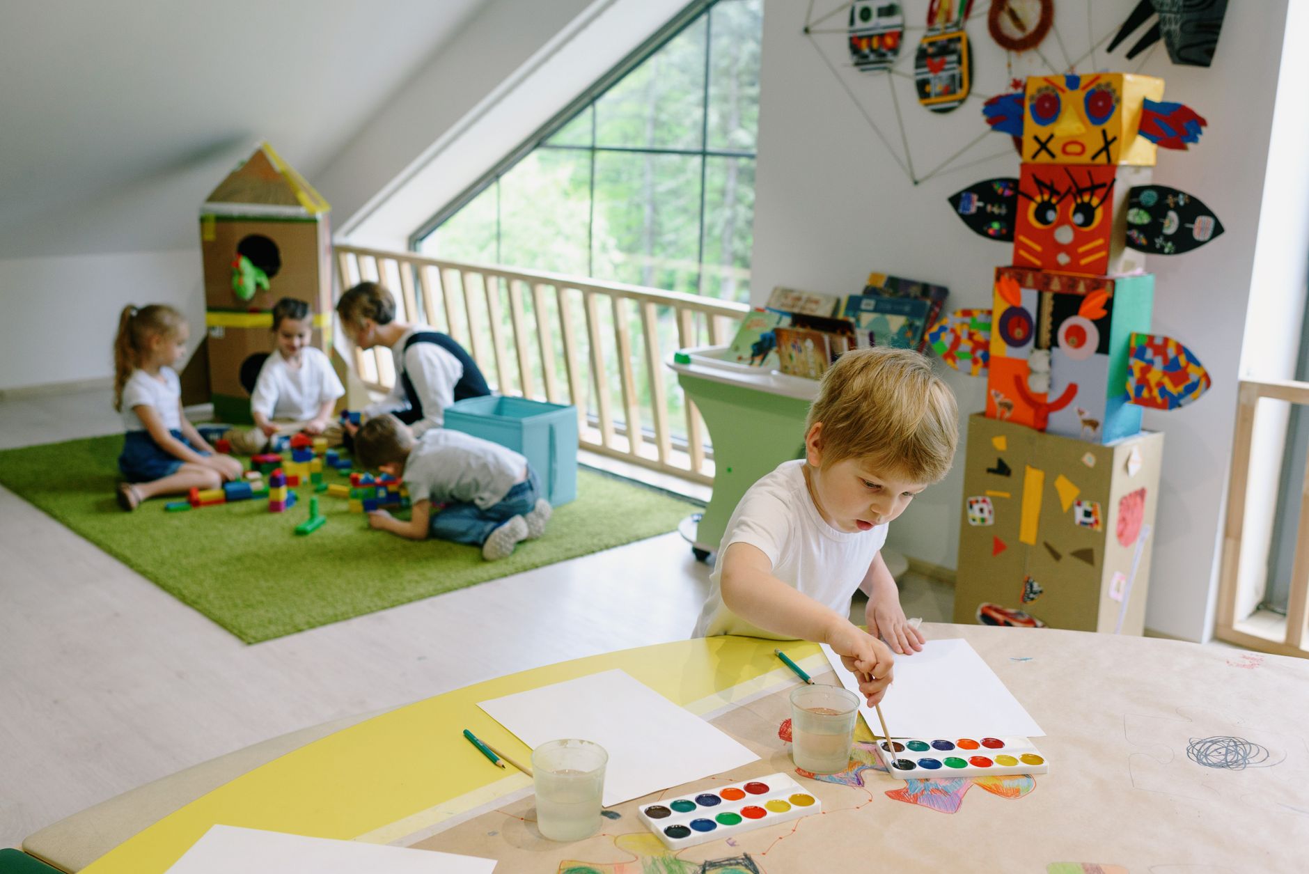 Kids painting and playing with blocks in a bright, colorful classroom.