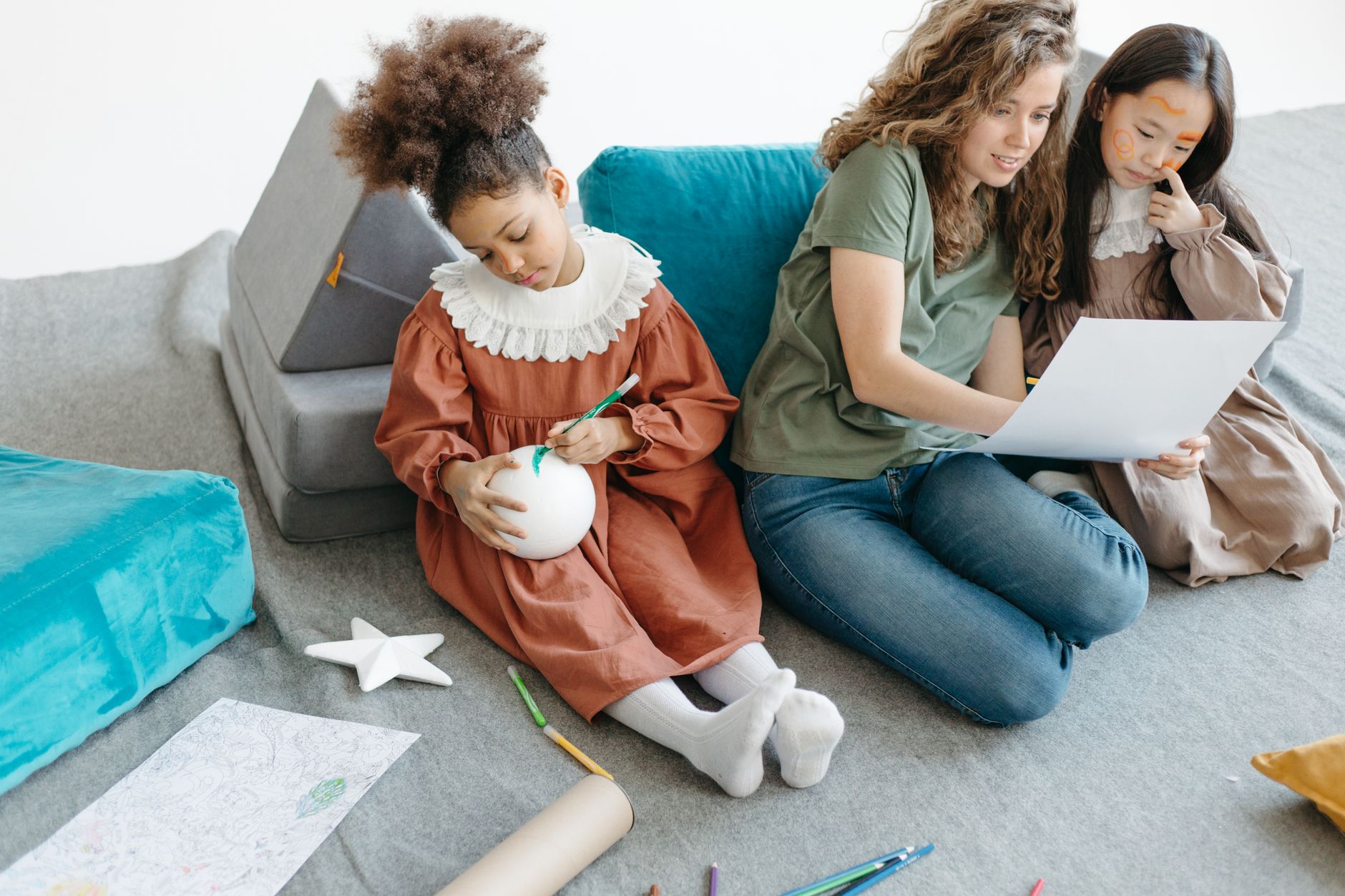 Teacher engaging children in creative activities with art materials in a cozy classroom setting.
