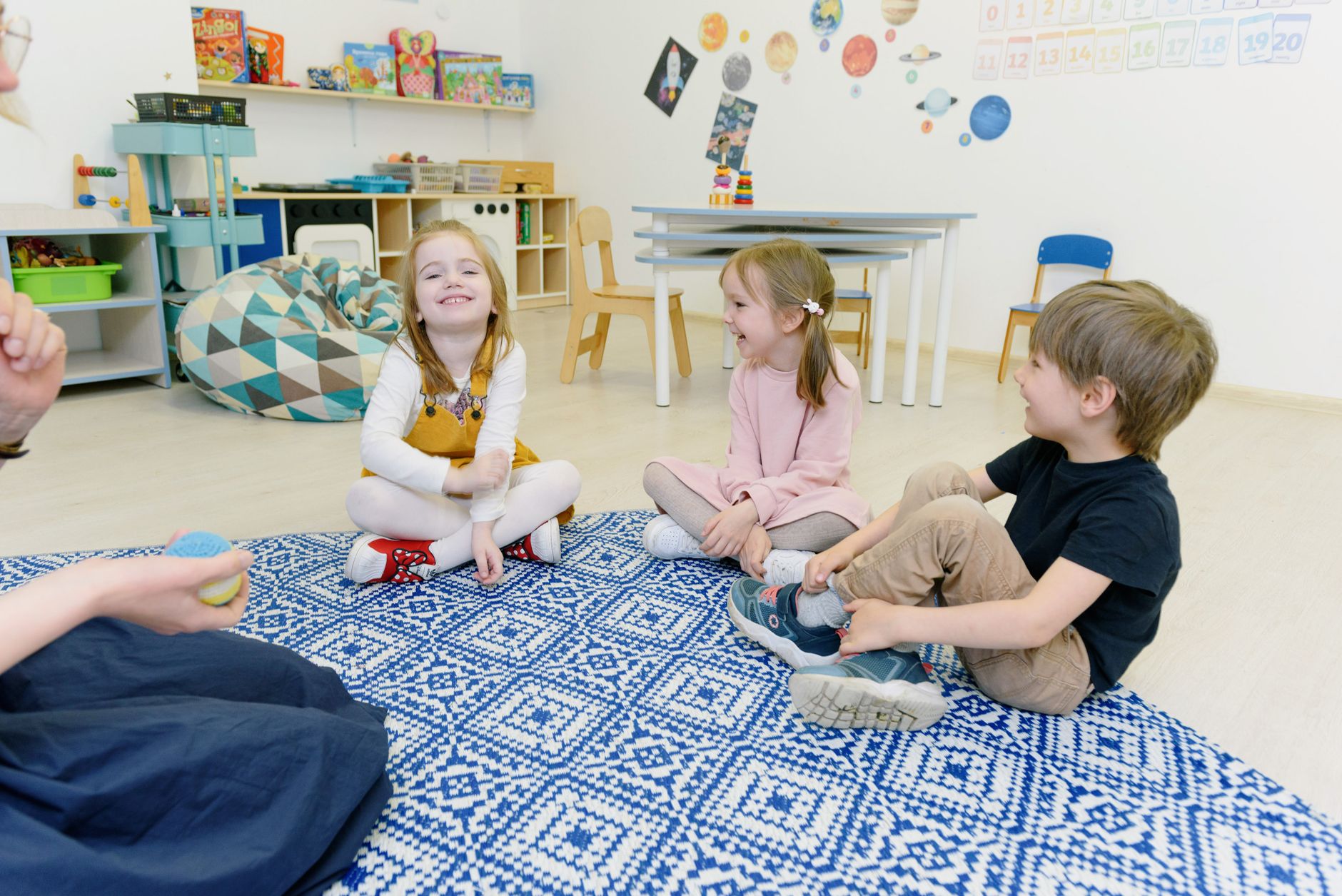 A group of young children happily playing together in a well-decorated kindergarten classroom.