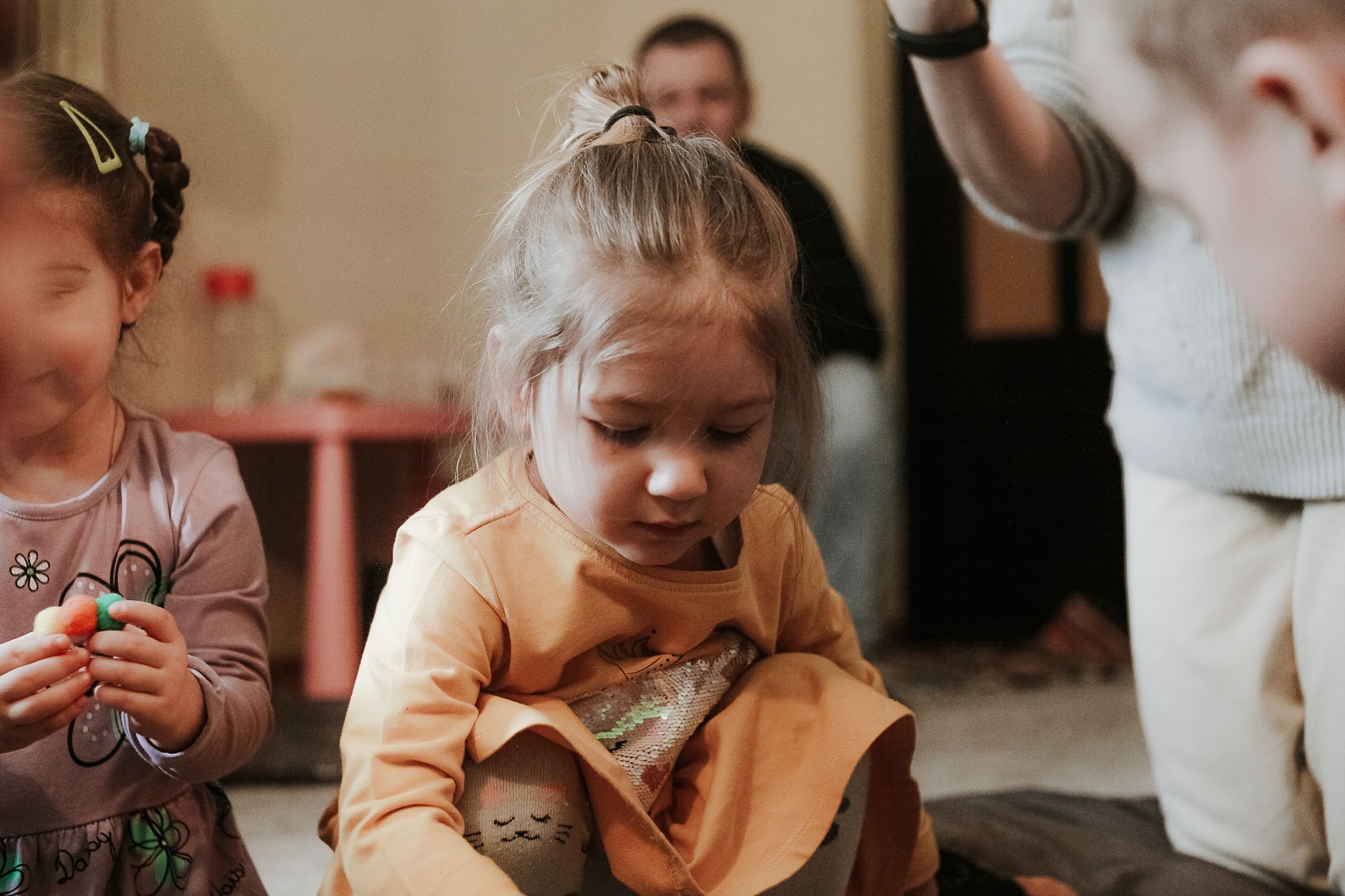 Young children engaged in play indoors, focused on creative activities
