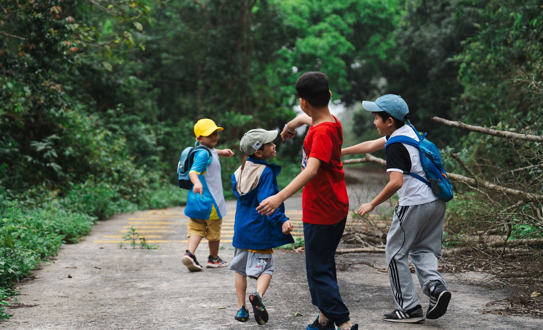 A group of children wearing backpacks enjoying a nature walk on a sunny day.