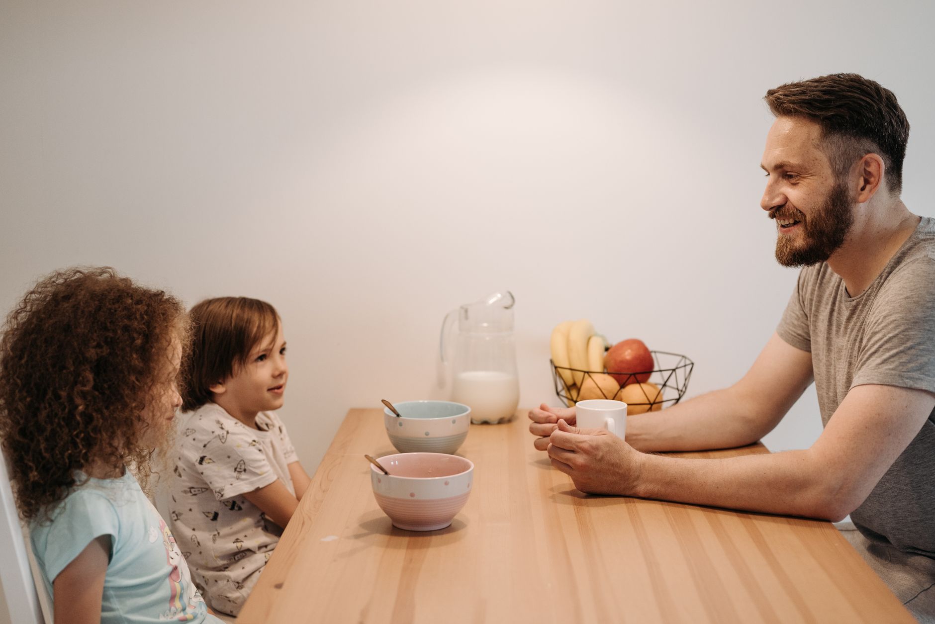 A father having a warm conversation with his children during breakfast at home.