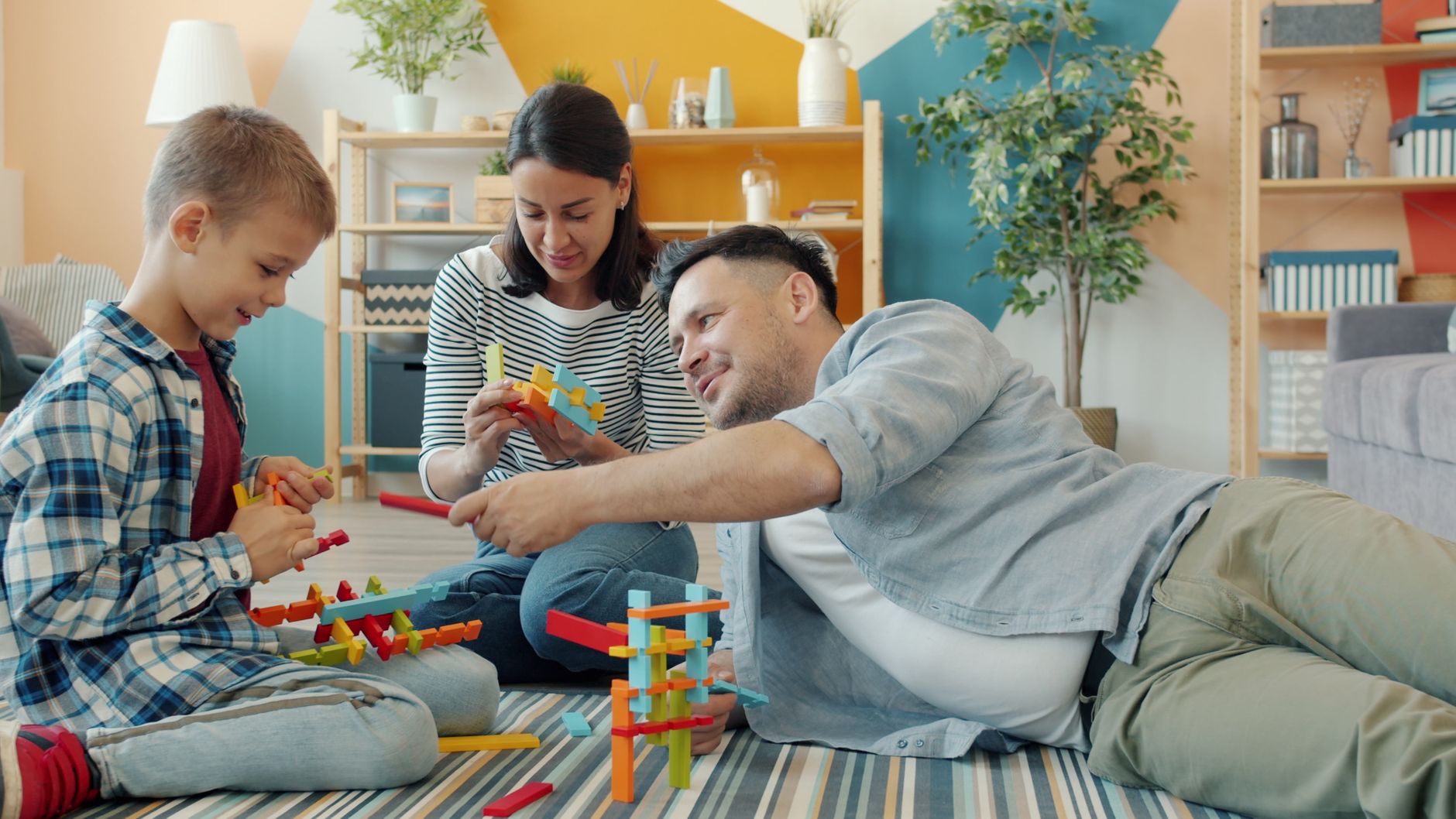 A family enjoying quality time together playing with colorful building blocks on the floor.