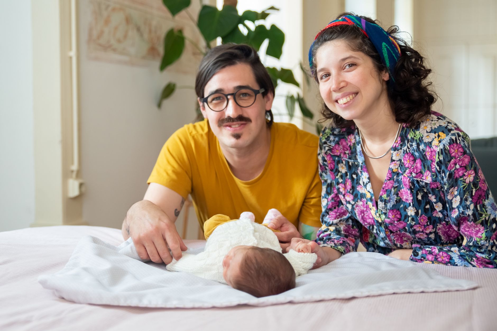 Smiling parents with a newborn baby at home, showcasing family love and togetherness.